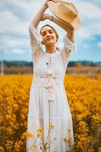 Young woman with closed eyes standing on field against sky