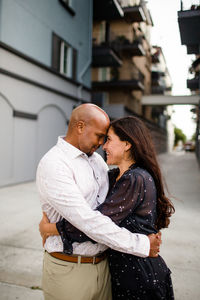 Side view of man and woman standing against building in city