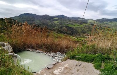 Scenic view of river by mountains against sky