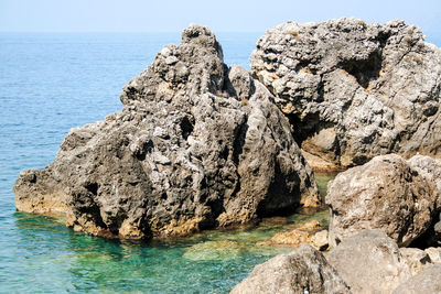 Rock formation in sea against sky