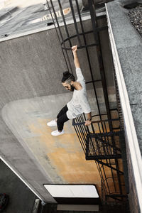 High angle view of man sitting on ladder against building