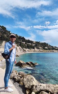 Full length of man standing on rock by sea against sky