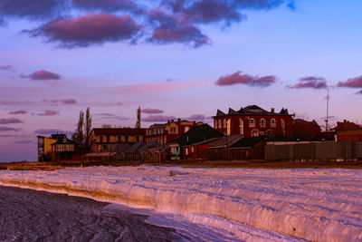 Houses by buildings against sky during winter