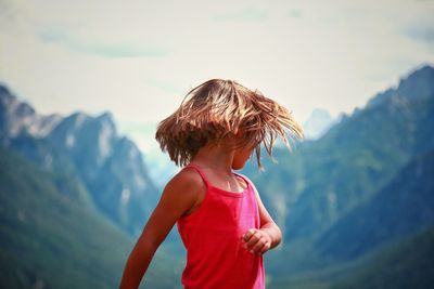 Blond girl tossing hair against mountains