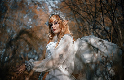 Young woman with arms raised in forest