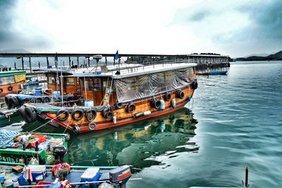 Boats moored at harbor against sky