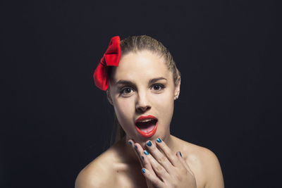 Portrait of shirtless young woman holding eyeglasses against black background