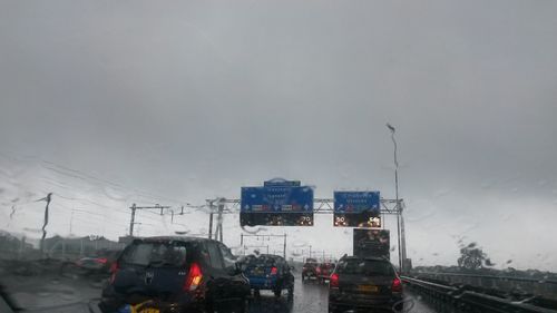 Cars on road against cloudy sky