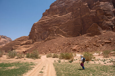 Woman walking on field against rock formation