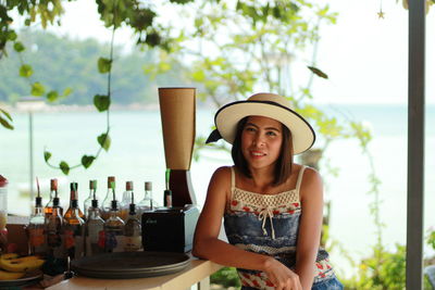 Portrait of woman sitting at bar counter against sea
