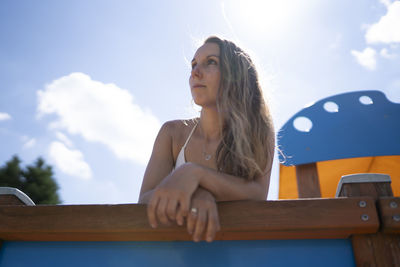 Low angle view of woman sitting on table against sky