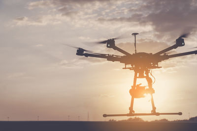 Electricity pylon against cloudy sky during sunset