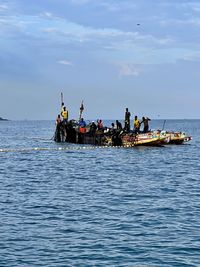 People on boat in sea against sky