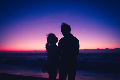 Silhouette woman standing on beach against sky during sunset