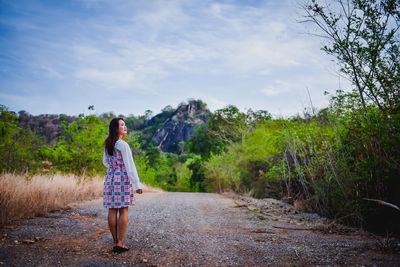 Rear view of woman standing by plants against sky