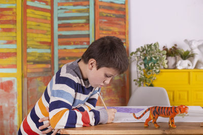 Boy drawing at table, indoors.