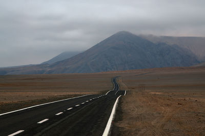 Road leading towards mountains against sky