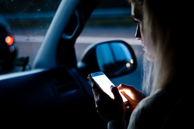 Cropped image of woman using smart phone in car