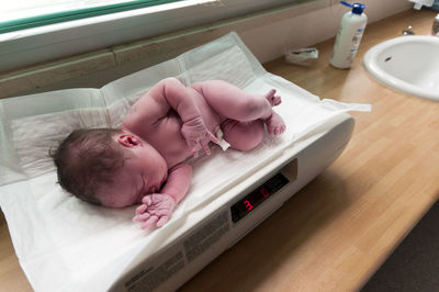 High angle view of newborn baby on weight scale at hospital