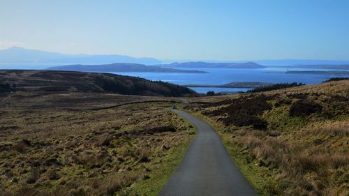 Road leading towards mountains against blue sky