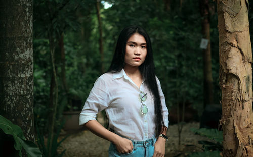 Portrait of young woman standing in forest