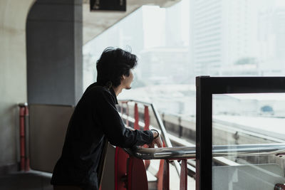 Side view of woman looking through window