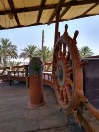 Metallic structure by palm trees against sky