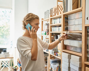 Female entrepreneur using phone while working in factory