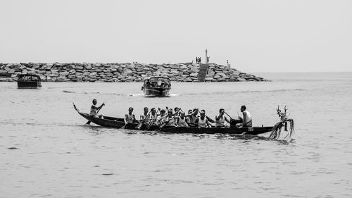 People on boat sailing in sea against clear sky