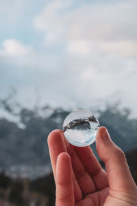 Close-up of hand holding glass against water