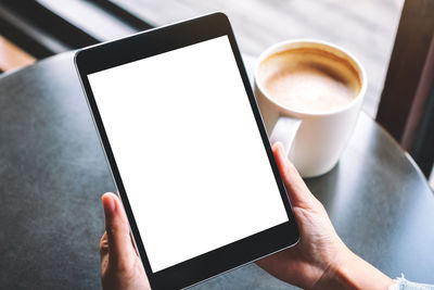 Cropped image of hand holding coffee cup on table