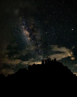 Silhouette people on mountain against sky at night