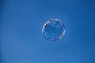 Low angle view of bubbles against blue sky