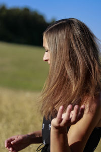 Side view of a young woman wearing hat on field