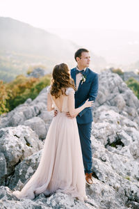 Side view of couple standing on rock