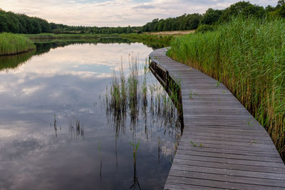 Boardwalk by lake against sky