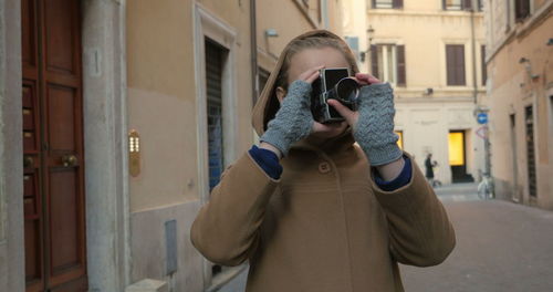 Full length of woman photographing while standing on street