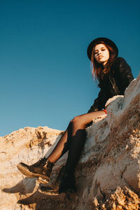 Low angle view of young woman against clear sky