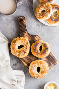 Bagels with poppy seeds and sesame seeds on a plate and a cup of coffee on the table.