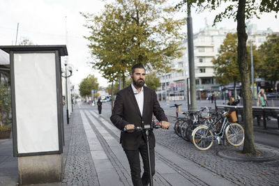 Businessman riding electric push scooter in city