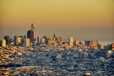 Aerial view of buildings in city against sky during sunset