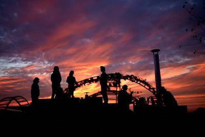 Silhouette people by sea against sky during sunset