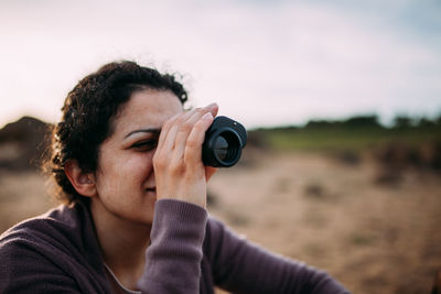 Woman looking through binocular on field