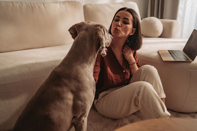 Portrait of young woman with dog at home