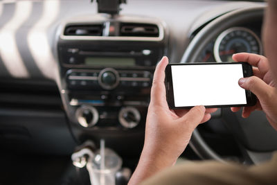 Cropped hand of man using phone in car
