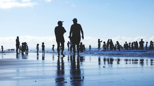 Silhouette people on beach against sky