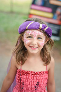 Portrait of cheerful girl with face paint standing on field