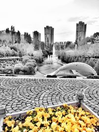 Footpath by street and buildings against sky