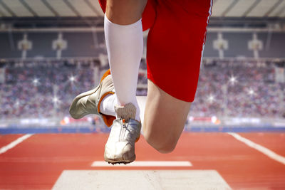 Low section of sportsperson jumping at stadium