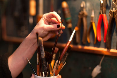 Close-up of hand holding paint brushes at workshop